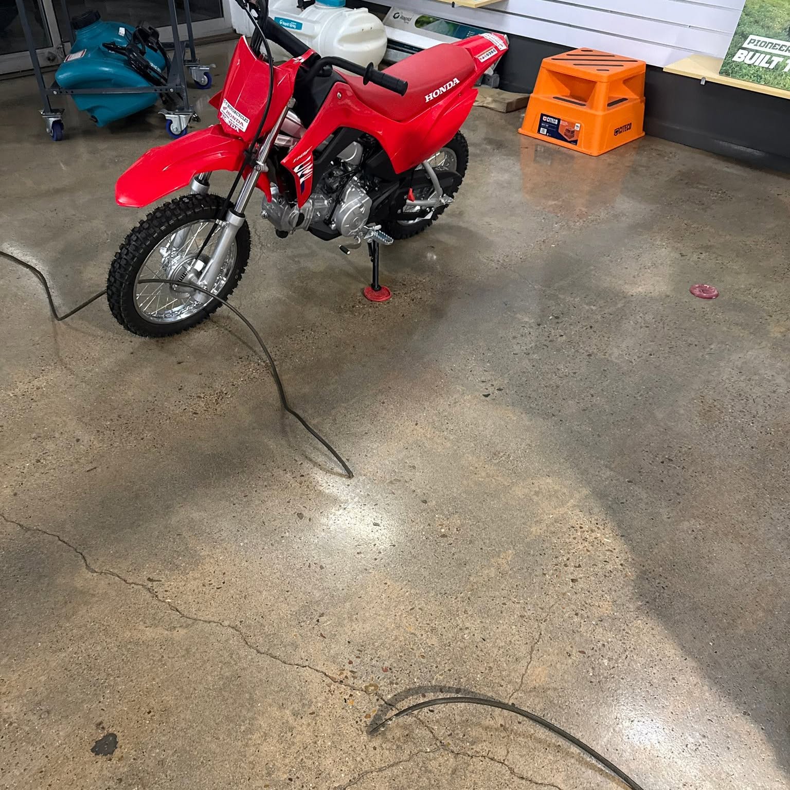 A Honda CRF110 trail bike on the workshop floor
