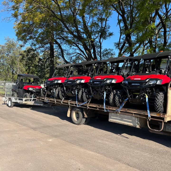 A truck and trailer loaded with new Honda Pioneer side by sides arriving at the shop
