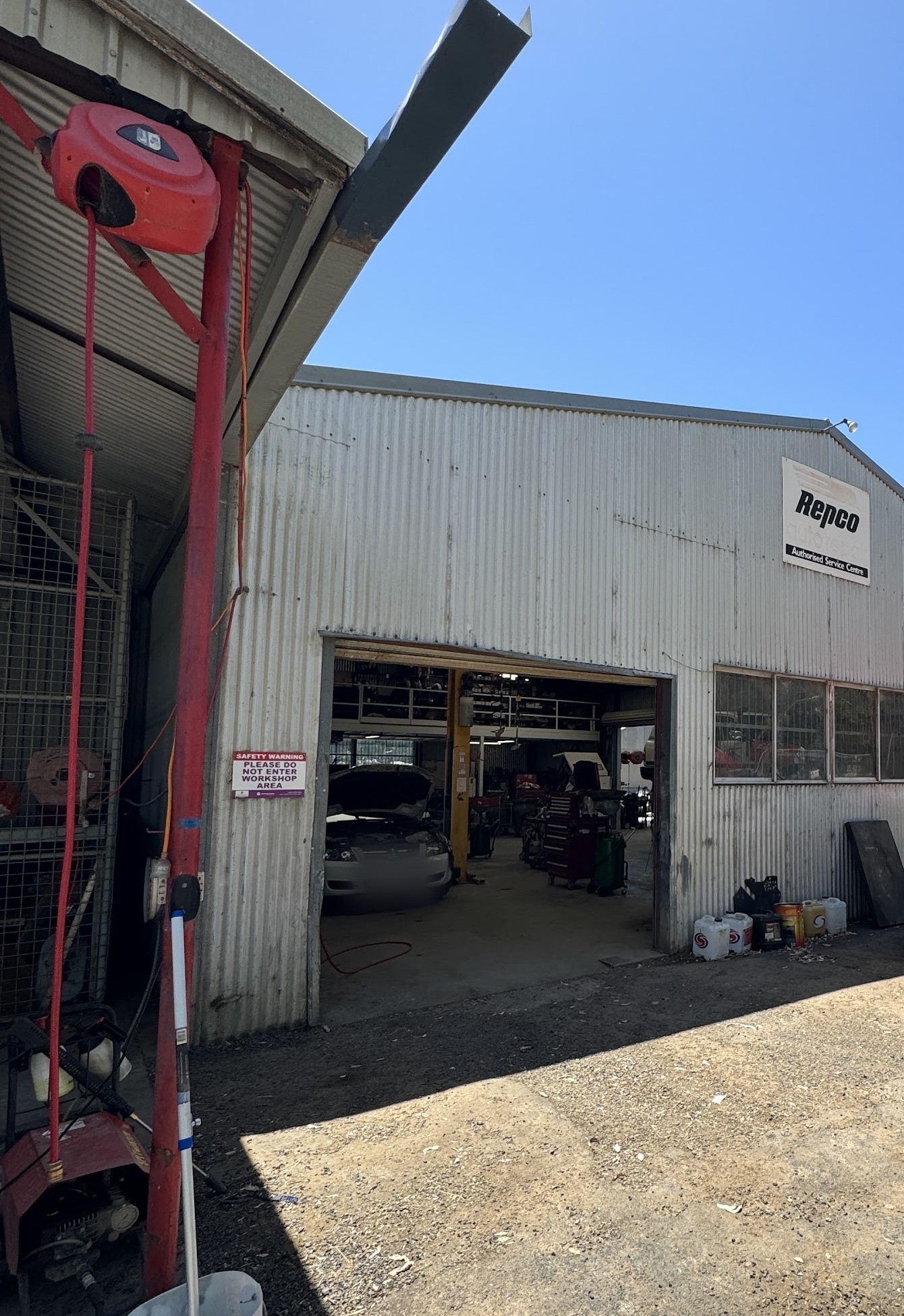 The workshop shed at Tony McLaughlin Mechanical Repairs, roller door open and the Repco Authorised Service Centre sign on the gable