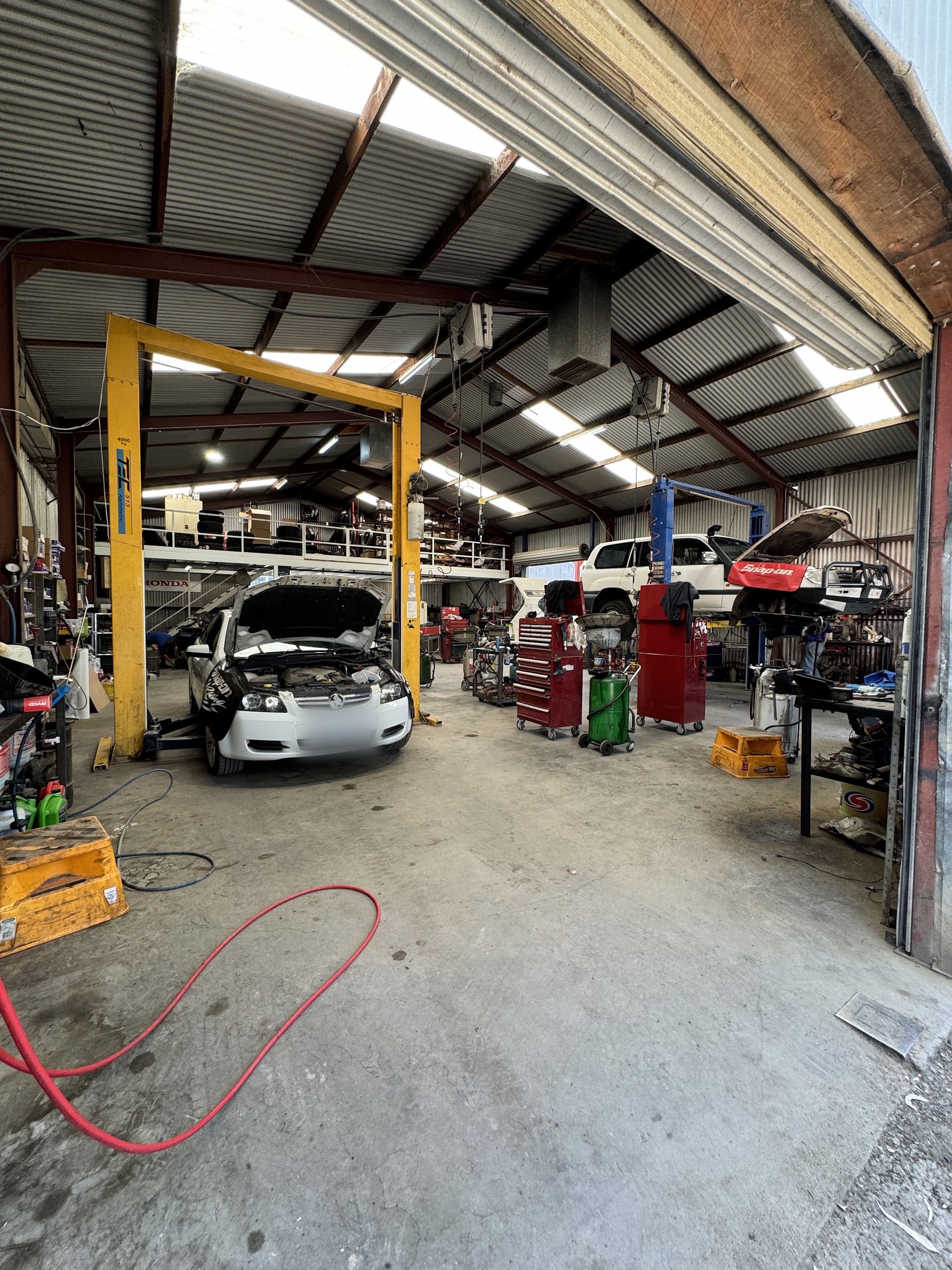 The workshop floor with a ute on the four tonne hoist and a 4WD behind it