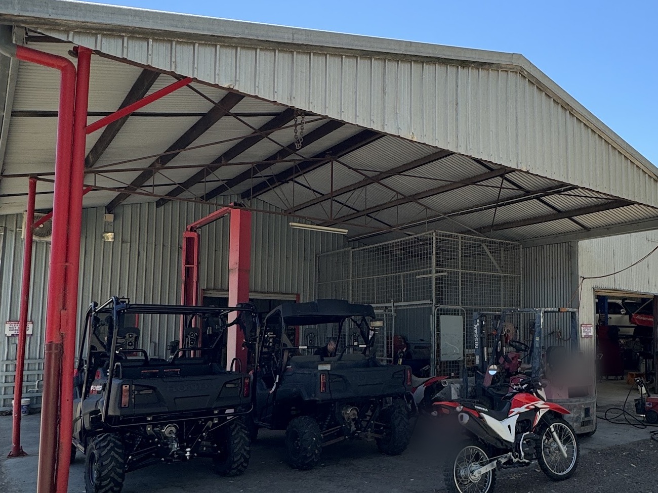 Honda Pioneer side by sides and a Honda trail bike parked in the covered bay